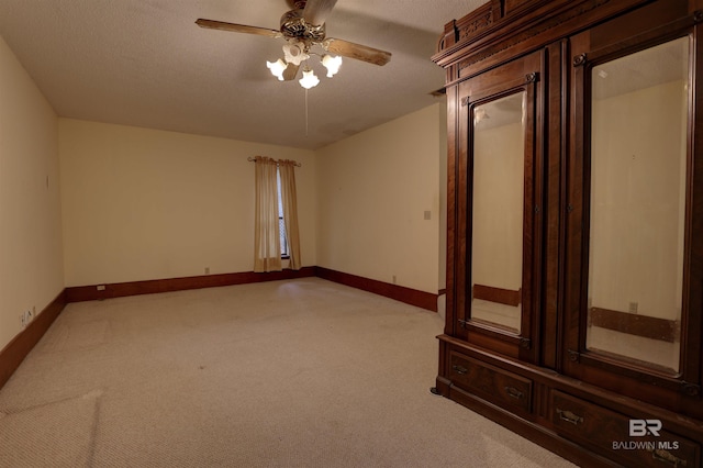 unfurnished room featuring a textured ceiling, ceiling fan, and light carpet