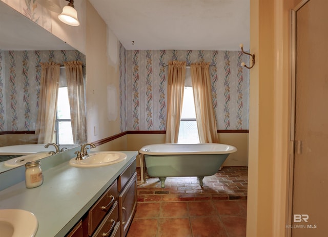 bathroom with tile patterned floors, plenty of natural light, a tub to relax in, and vanity