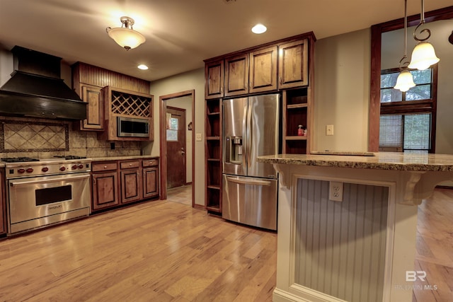 kitchen featuring a breakfast bar, light hardwood / wood-style flooring, decorative backsplash, custom range hood, and stainless steel appliances