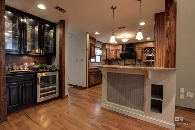 kitchen featuring a breakfast bar, wine cooler, light wood-type flooring, appliances with stainless steel finishes, and custom range hood