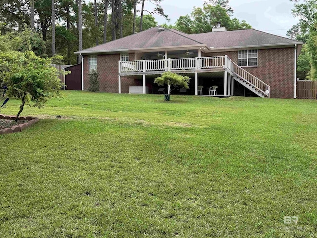 rear view of house featuring a lawn, brick siding, a deck, and stairs