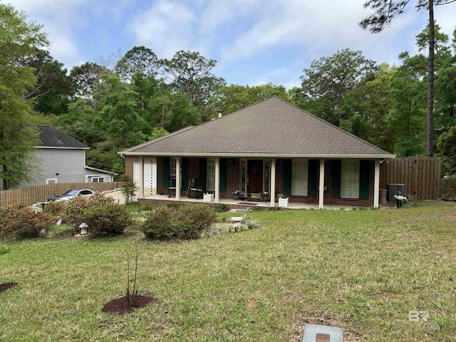 view of front of home with a porch, a front yard, fence, and brick siding