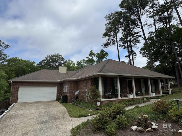 single story home featuring an attached garage, covered porch, a chimney, brick siding, and driveway