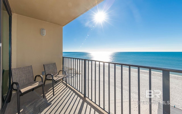 balcony featuring a view of the beach and a water view