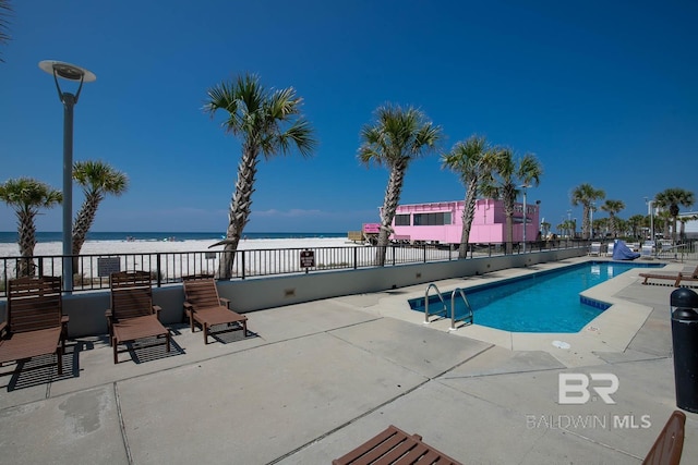 view of pool featuring a beach view, a water view, and a patio area