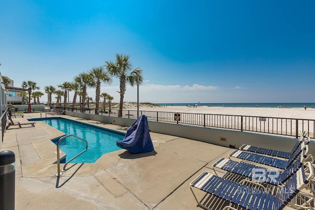 view of swimming pool featuring a beach view, a patio area, and a water view