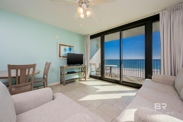 tiled living room with ceiling fan and floor to ceiling windows