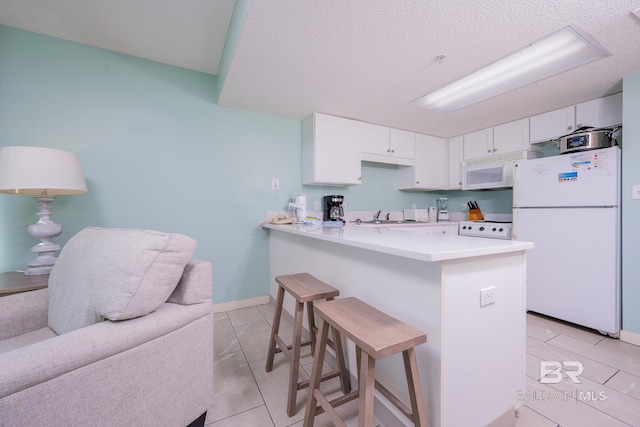 kitchen featuring white appliances, kitchen peninsula, a breakfast bar, white cabinets, and light tile patterned flooring