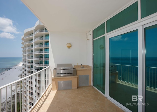 balcony with a grill, sink, a beach view, and a water view