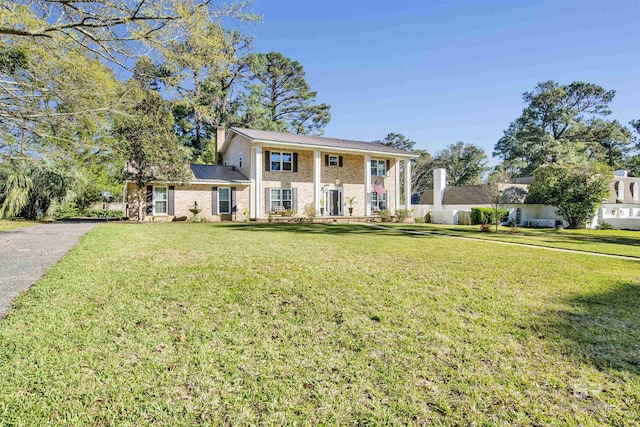 greek revival house with metal roof, a front lawn, aphalt driveway, and brick siding