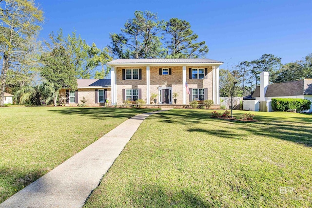 view of front facade with metal roof, a front yard, and brick siding