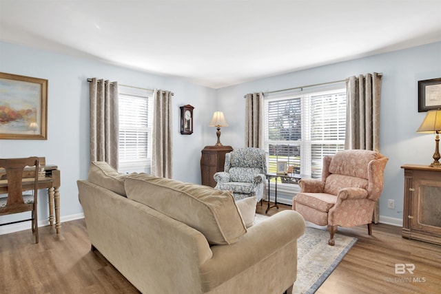 living area with a healthy amount of sunlight, light wood-style flooring, and baseboards