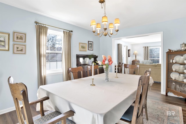 dining area with dark wood finished floors, baseboards, a notable chandelier, and a wealth of natural light