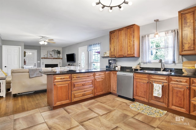 kitchen with a sink, brown cabinets, a healthy amount of sunlight, a peninsula, and stainless steel dishwasher