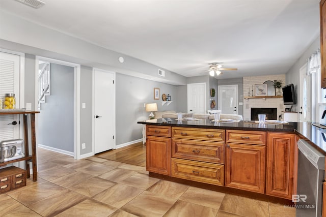 kitchen featuring brown cabinets, stainless steel dishwasher, ceiling fan, visible vents, and a fireplace