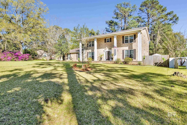 view of front of house with brick siding, fence, and a front yard