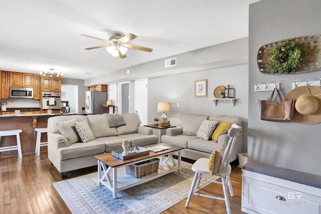 living area featuring hardwood / wood-style floors, visible vents, and a ceiling fan