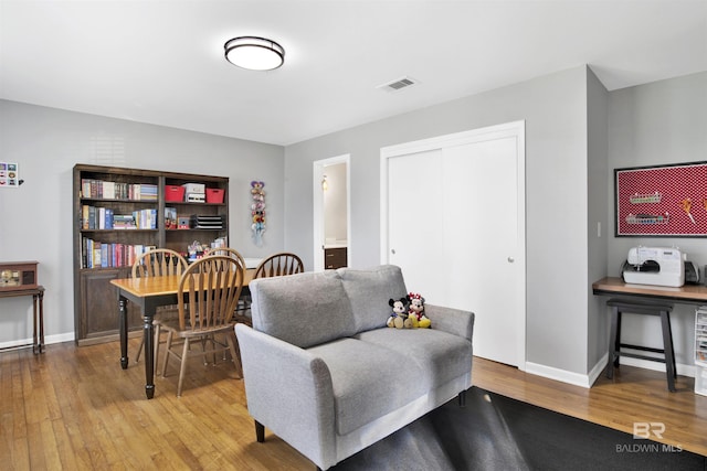 living area featuring baseboards, visible vents, and wood finished floors