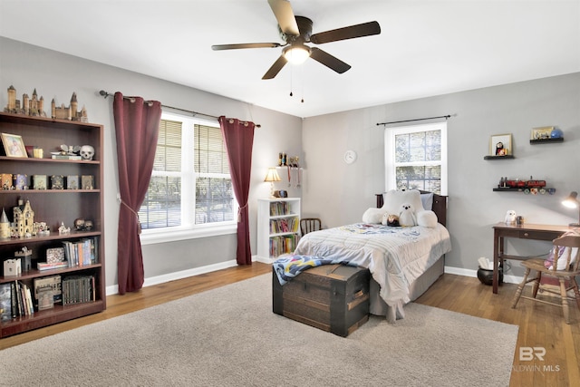 bedroom featuring multiple windows, wood finished floors, and baseboards