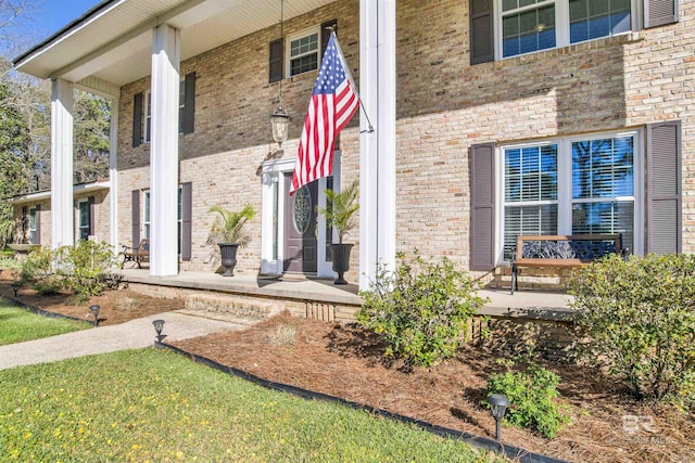 entrance to property featuring covered porch and brick siding