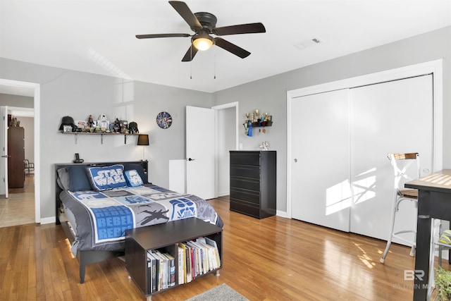 bedroom with a closet, ceiling fan, visible vents, baseboards, and wood finished floors