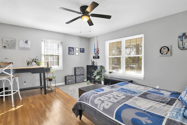 bedroom with ceiling fan, wood finished floors, and baseboards