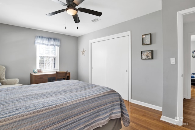 bedroom featuring wood finished floors, a closet, ceiling fan, baseboards, and visible vents