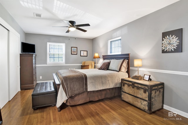 bedroom with baseboards, visible vents, wood finished floors, and a ceiling fan