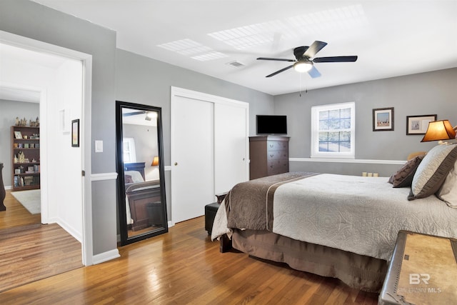 bedroom featuring baseboards, wood finished floors, a ceiling fan, and a closet