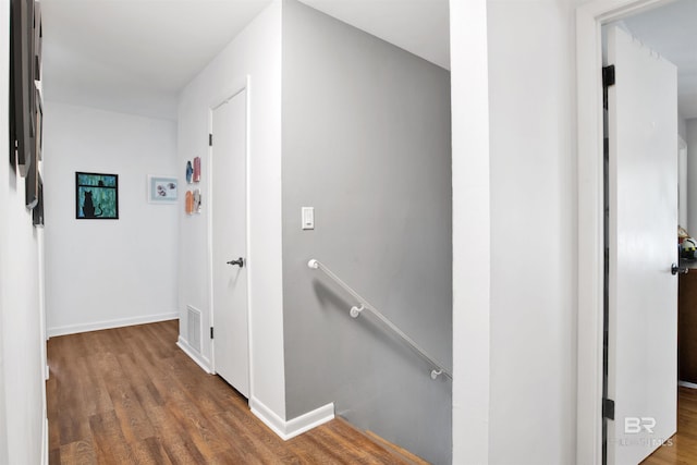 hallway featuring an upstairs landing, wood finished floors, visible vents, and baseboards