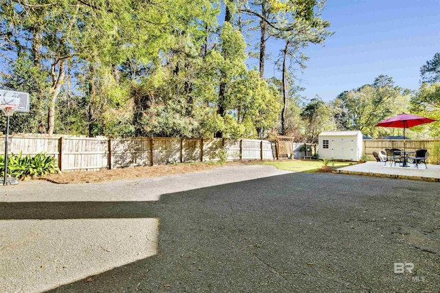 view of yard featuring a fenced backyard, an outbuilding, outdoor dining area, a patio area, and a shed