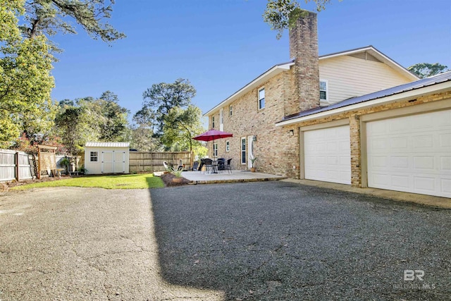 exterior space featuring a chimney, an outdoor structure, a fenced backyard, a storage shed, and driveway