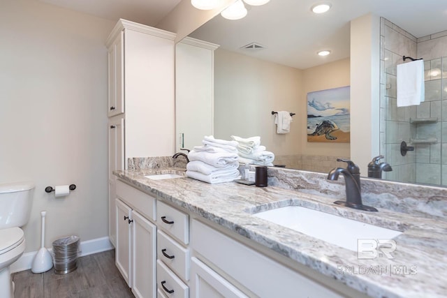 bathroom featuring vanity, wood-type flooring, tiled shower, toilet, and ceiling fan