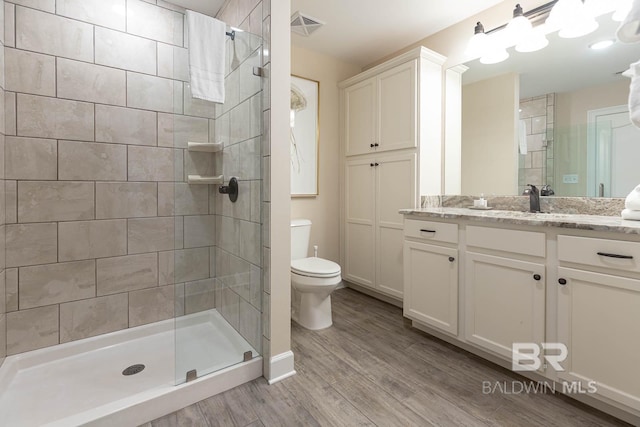 bathroom with hardwood / wood-style floors, walk in shower, toilet, and vanity