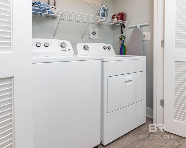 laundry room with separate washer and dryer and light hardwood / wood-style flooring