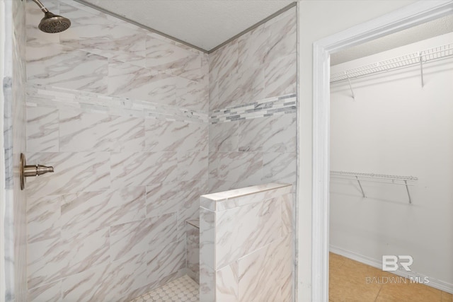 bathroom featuring a textured ceiling, tiled shower, and a walk in closet