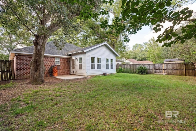 rear view of property with a fenced backyard, a patio, a lawn, and brick siding