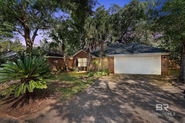 ranch-style house with aphalt driveway, brick siding, and an attached garage