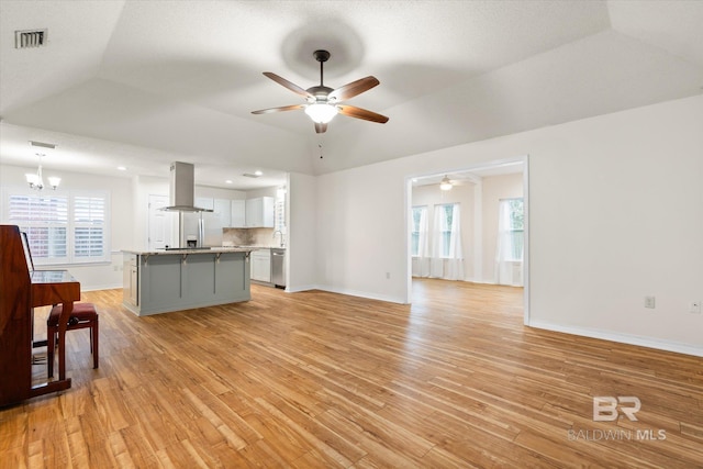 living room featuring ceiling fan with notable chandelier, light wood finished floors, visible vents, and baseboards