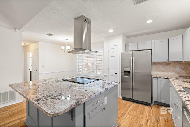 kitchen with gray cabinetry, visible vents, light wood-style floors, stainless steel fridge with ice dispenser, and island exhaust hood