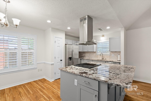 kitchen with tasteful backsplash, appliances with stainless steel finishes, island exhaust hood, gray cabinets, and a sink