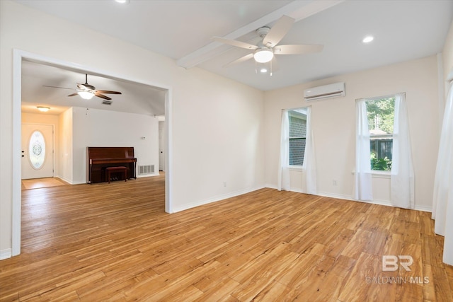 unfurnished room with light wood-type flooring, baseboards, visible vents, and an AC wall unit