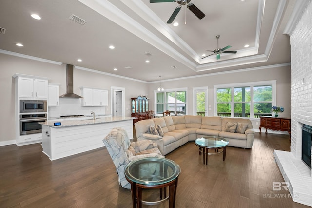 9377 Diamante Blvd, Daphne, AL 36526 - living room with ornamental molding, dark wood-style floors, a ceiling fan, visible vents, and a raised ceiling