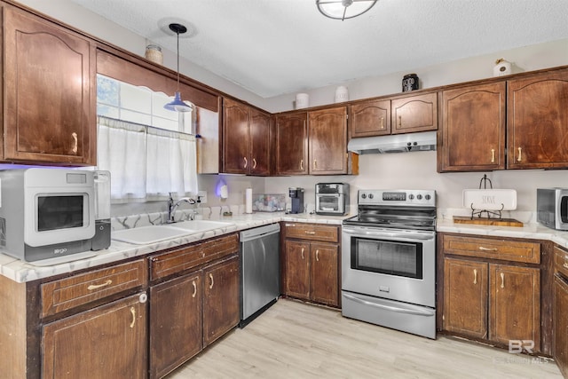 221 Howard Cir, Gulf Shores, AL 36542 - kitchen with appliances with stainless steel finishes, under cabinet range hood, light wood finished floors, light countertops, and a textured ceiling