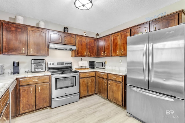221 Howard Cir, Gulf Shores, AL 36542 - kitchen featuring stainless steel appliances, under cabinet range hood, a textured ceiling, light wood finished floors, and light countertops