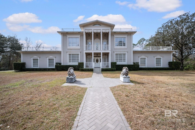 greek revival inspired property with a front lawn and a balcony