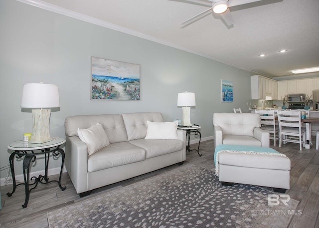 living room featuring wood-type flooring, crown molding, and ceiling fan