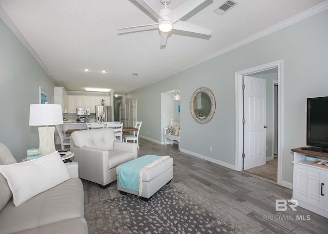 living room with light wood-type flooring, ceiling fan, ornamental molding, and a textured ceiling