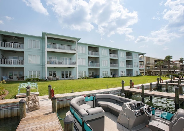 view of dock with an outdoor living space, a balcony, a water view, and a lawn