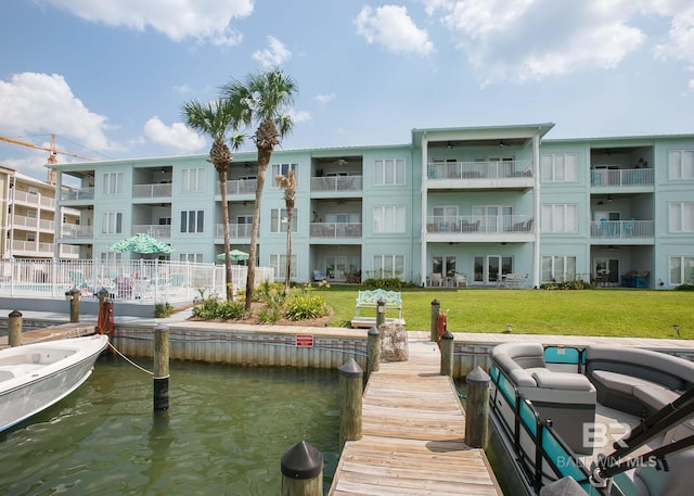 view of dock with a balcony, a water view, and a lawn